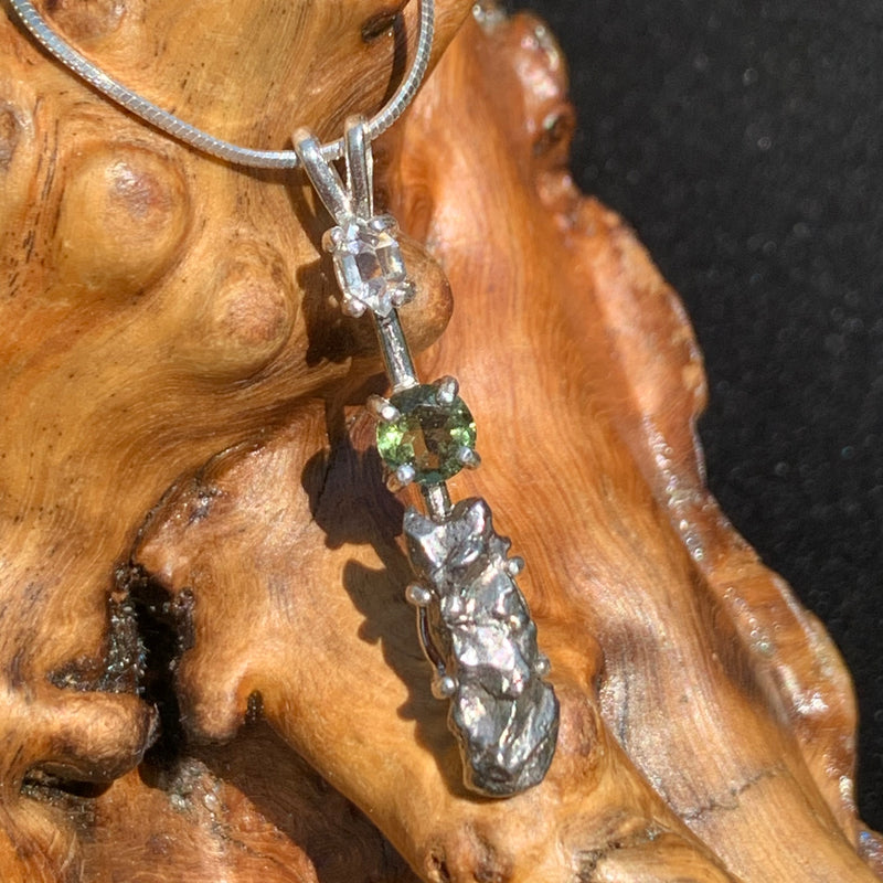 sterling silver pendant necklace with Herkimer diamond, moldavite, and campo del cielo meteorite sits on driftwood for display
