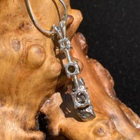 back side view of a sterling silver pendant necklace with Herkimer diamond, moldavite, and campo del cielo meteorite sitting on driftwood for display
