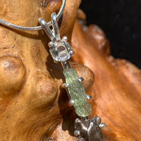 close up view of a sterling silver pendant necklace with Herkimer diamond, moldavite, and campo del cielo meteorite sitting on driftwood for display