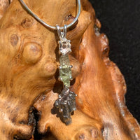 sterling silver pendant necklace with Herkimer diamond, moldavite, and campo del cielo meteorite sitting on driftwood for display