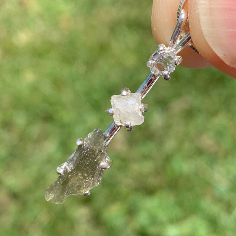 sterling silver pendant necklace with Herkimer diamond, moldavite, and phenacite is held up to show details