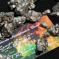 Several Campo pendants surround the Meteorite Identification card that comes with each pendant. 