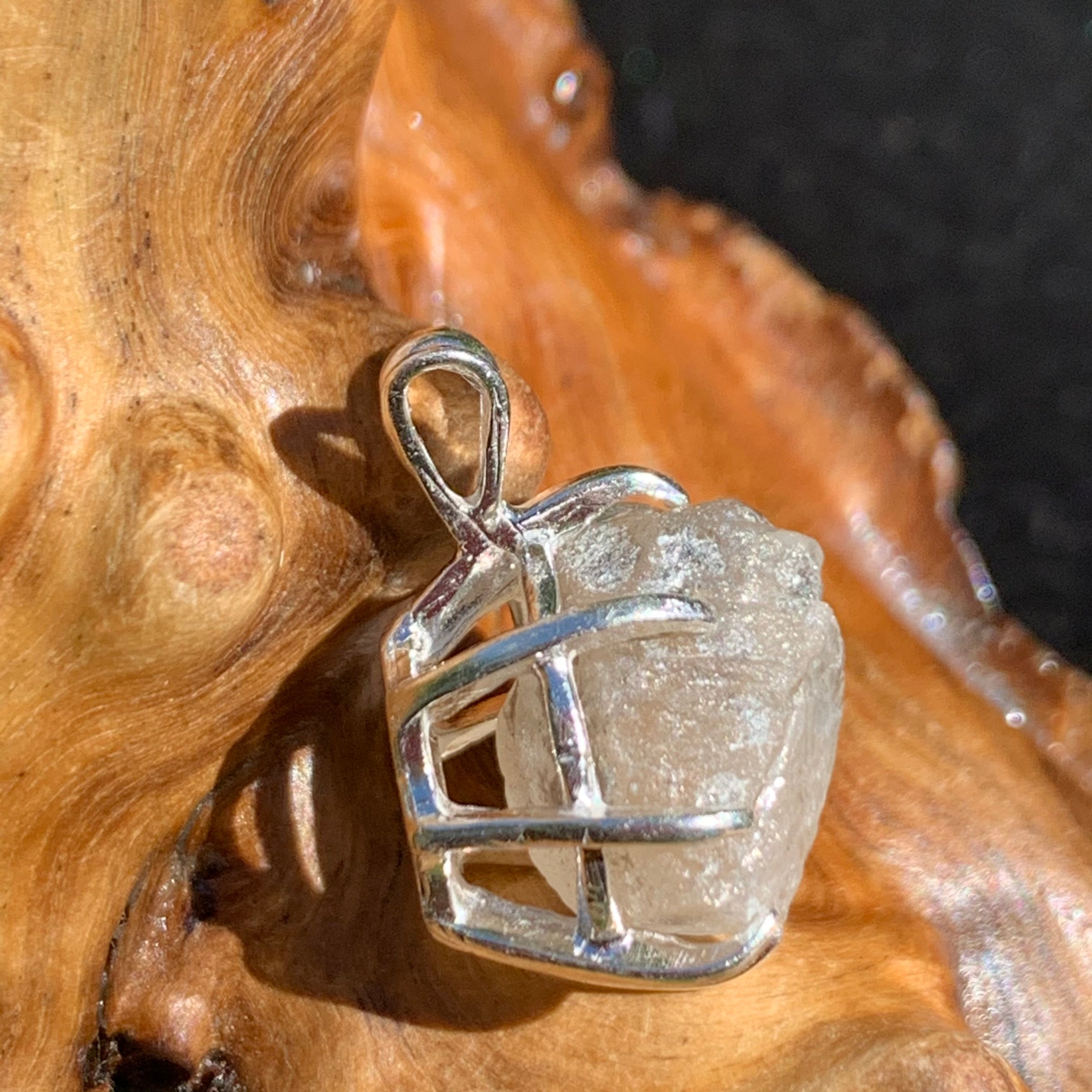sterling silver Russian phenacite basket pendant sitting on driftwood for display