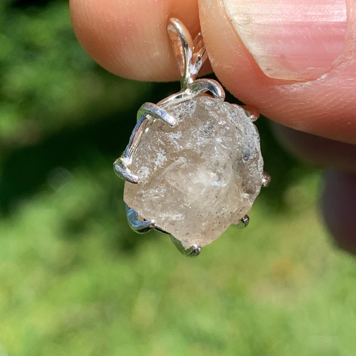 sterling silver Russian phenacite basket pendant held up on display