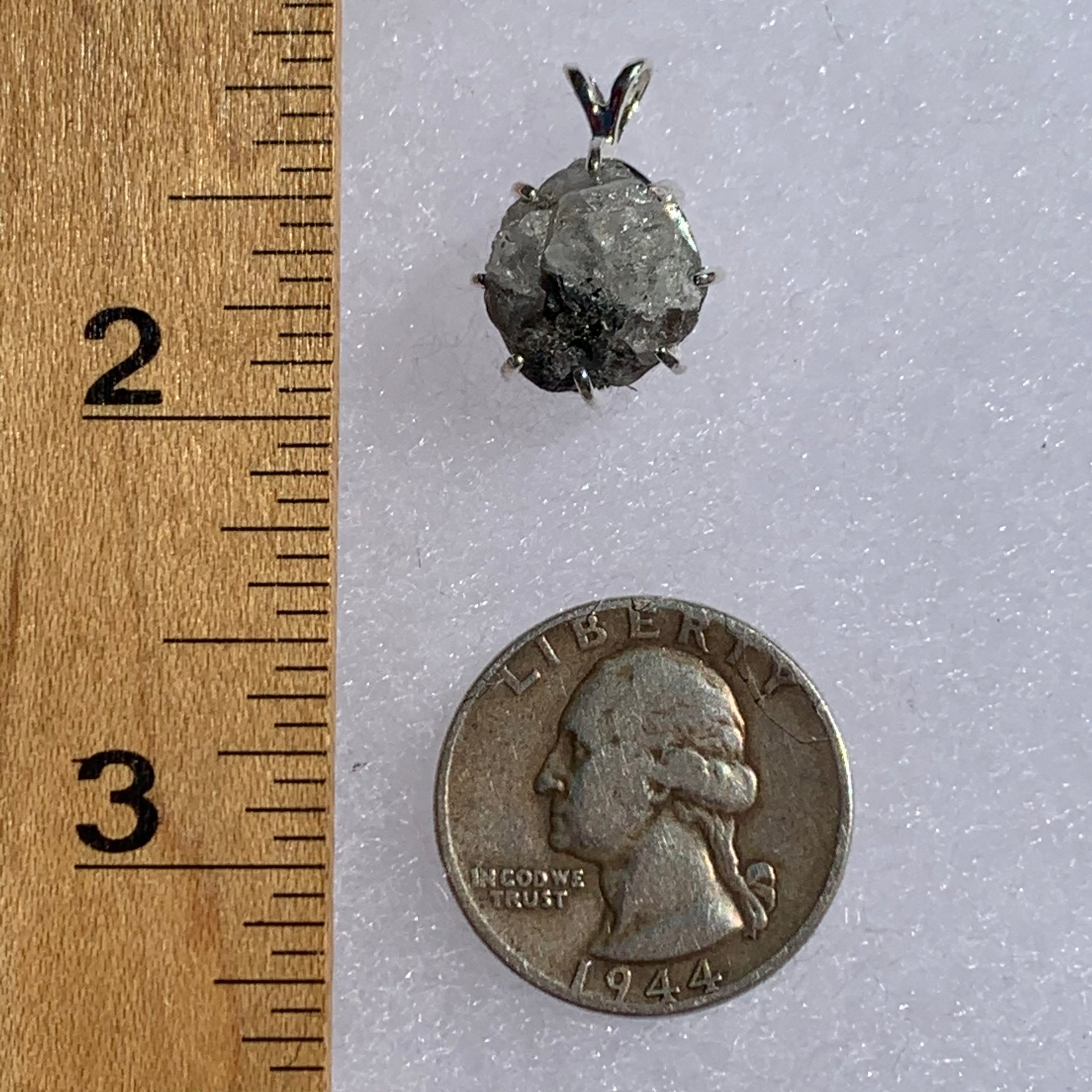 sterling silver Russian phenacite basket pendant next to a ruler and US quarter for scale