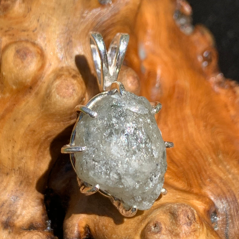 sterling silver moldavite tektite and Russian phenacite basket pendant sitting on driftwood for display