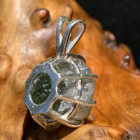 sterling silver moldavite tektite and Russian phenacite basket pendant sitting on driftwood for display