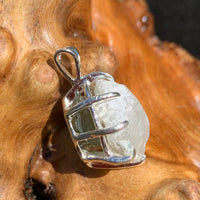 sterling silver moldavite tektite and Russian phenacite basket pendant sitting on driftwood for display