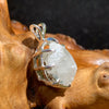 sterling silver moldavite tektite and Russian phenacite basket pendant sitting on driftwood for display