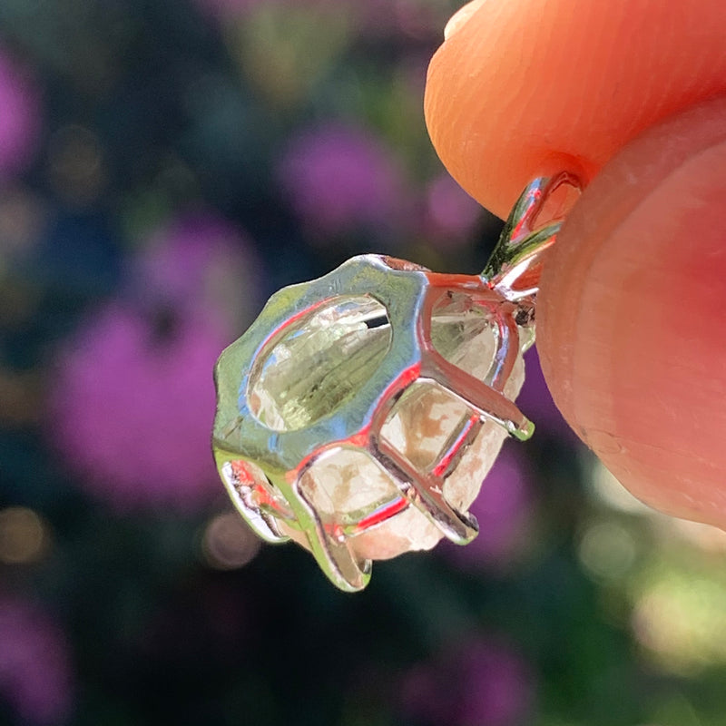 sterling silver moldavite tektite and Russian phenacite basket pendant held up on display