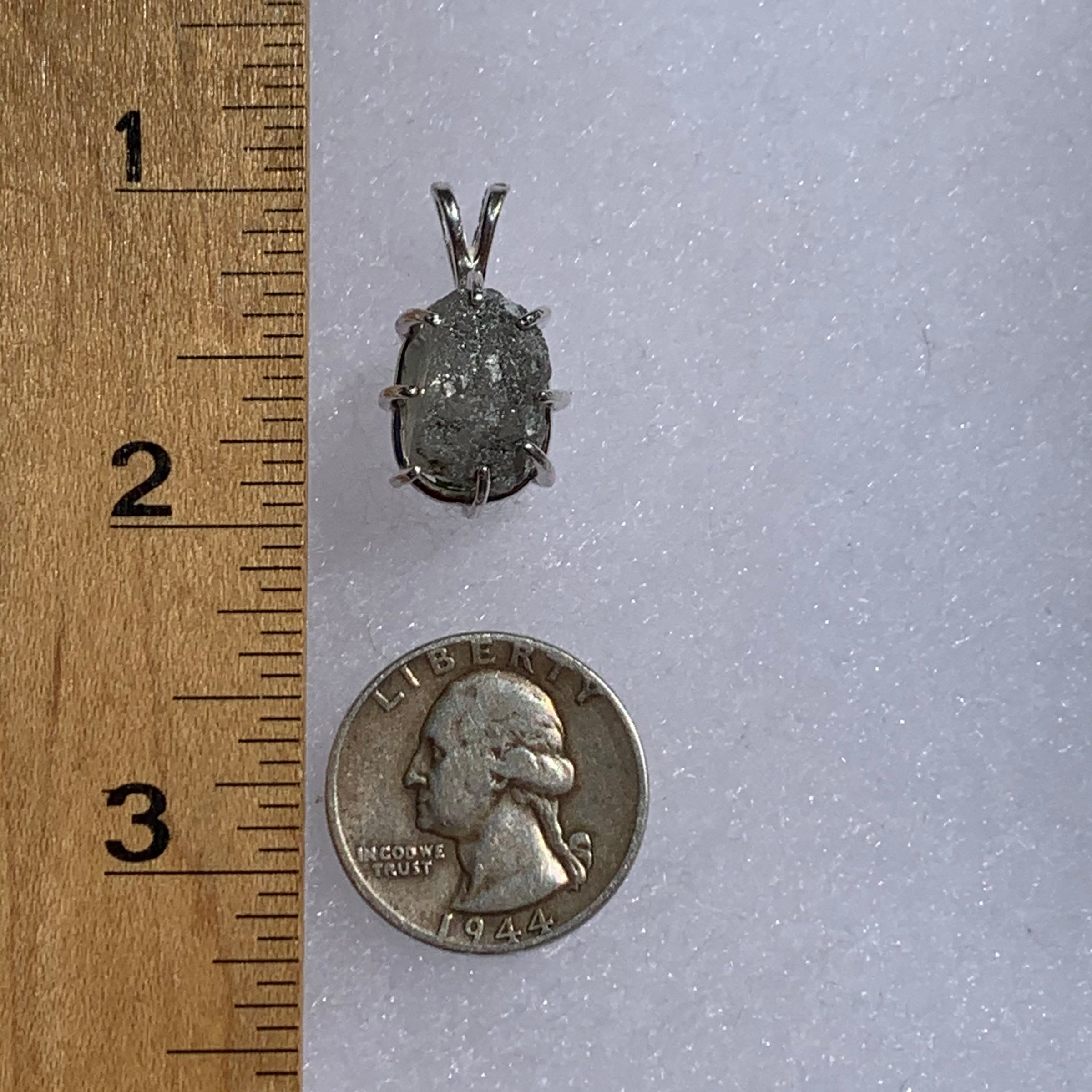 sterling silver moldavite tektite and Russian phenacite basket pendant next to a ruler and US quarter for scale