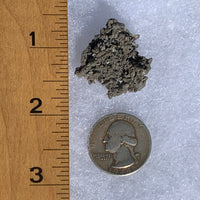 Gray quartz cluster with tiny black brookite in matrix next to ruler and quarter for scale