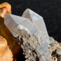 Gray quartz cluster with tiny black brookite in matrix displayed on driftwood