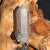 Gray quartz point with tiny black brookite in matrix displayed on driftwood