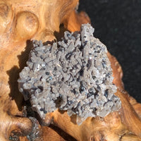 Gray quartz cluster with tiny black brookite in matrix displayed on driftwood