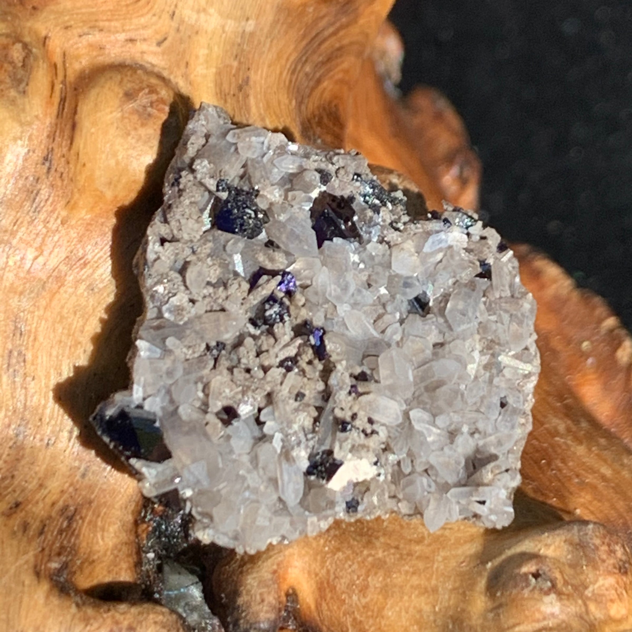 large and small brookite crystals on a smokey quartz point cluster sitting on driftwood for display