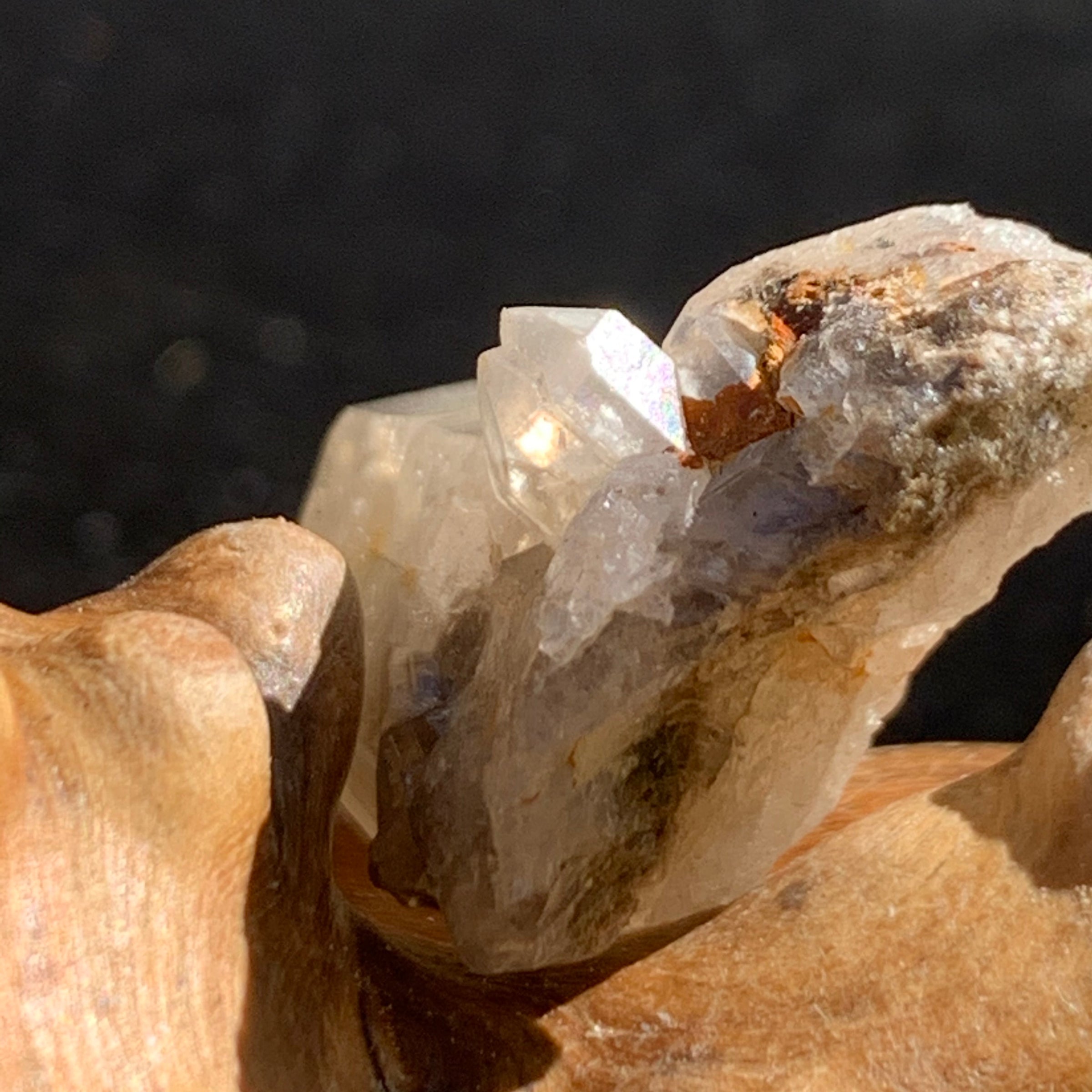 smokey quartz point cluster with tiny brookite on it sitting on driftwood for display