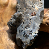 close up view of small and tiny brookite crystals on a smokey quartz point cluster sitting on driftwood for display