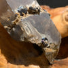close up view of medium, small, and tiny brookite crystals on a smokey quartz point sitting on driftwood for display