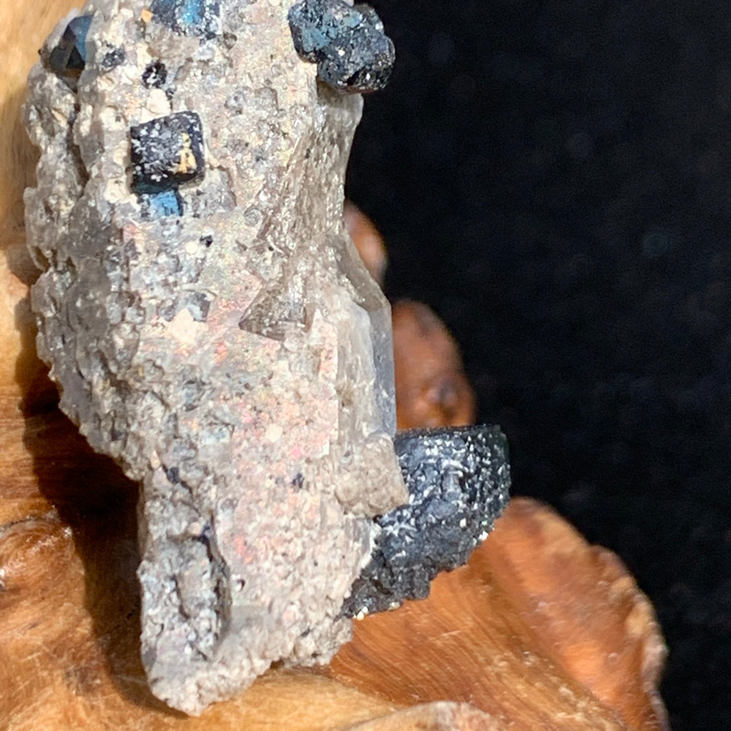 close up view of big and small brookite crystals on a smokey quartz point sitting on driftwood for display
