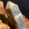 close up view of tiny brookite crystal on a smokey quartz point sitting on driftwood for display