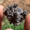 tiny brookite crystals on a smokey quartz cluster held in hand with the sunlight shining on it