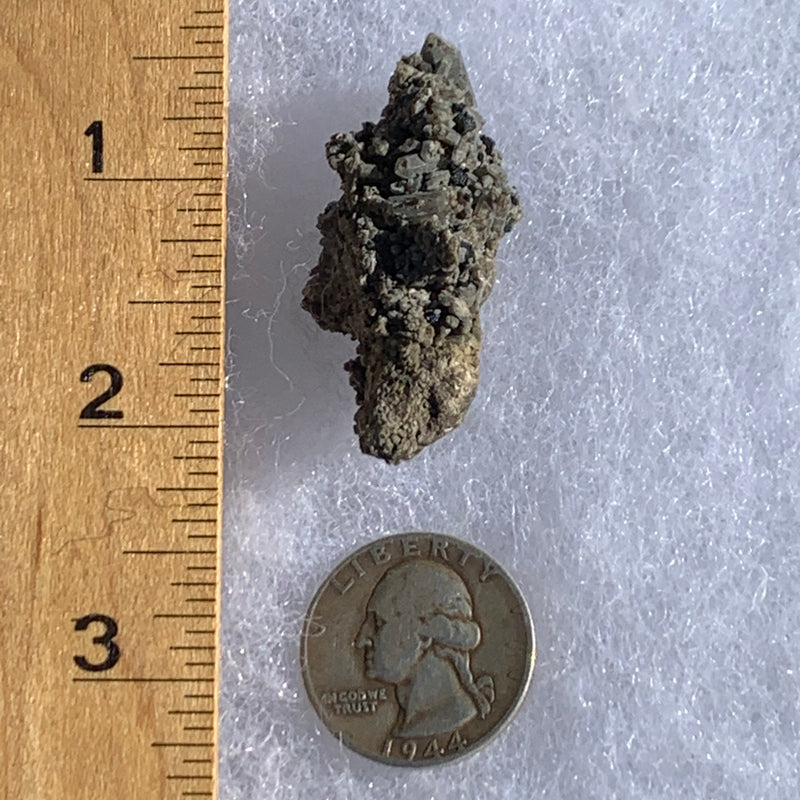 small and tiny brookite crystals on a smokey quartz point cluster next to a ruler and a quarter for scale