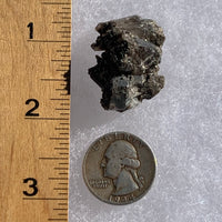 tiny brookite crystals on a smokey quartz cluster next to a ruler and a quarter for scale