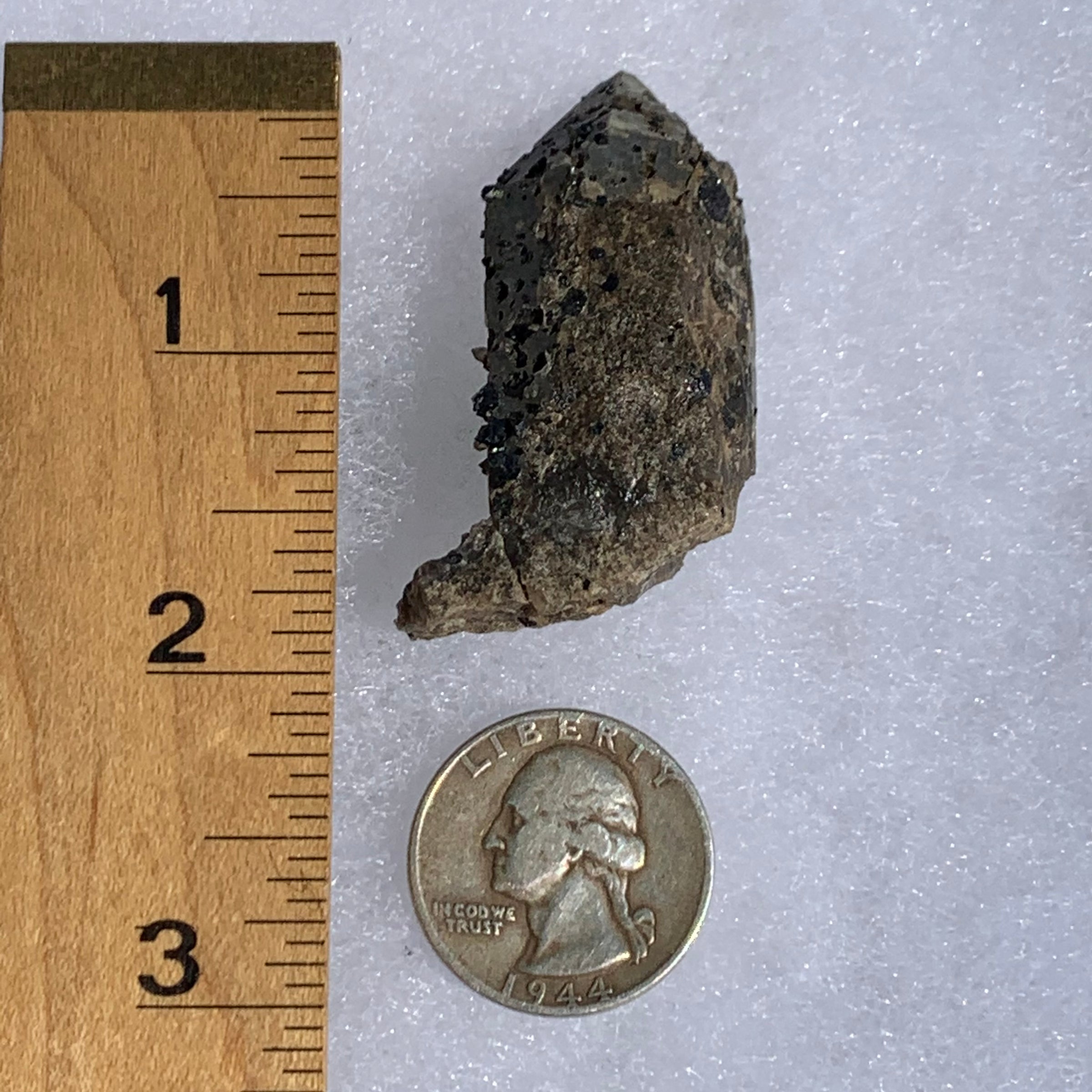 small and tiny brookite crystals on a smokey quartz point next to a ruler and a quarter for scale