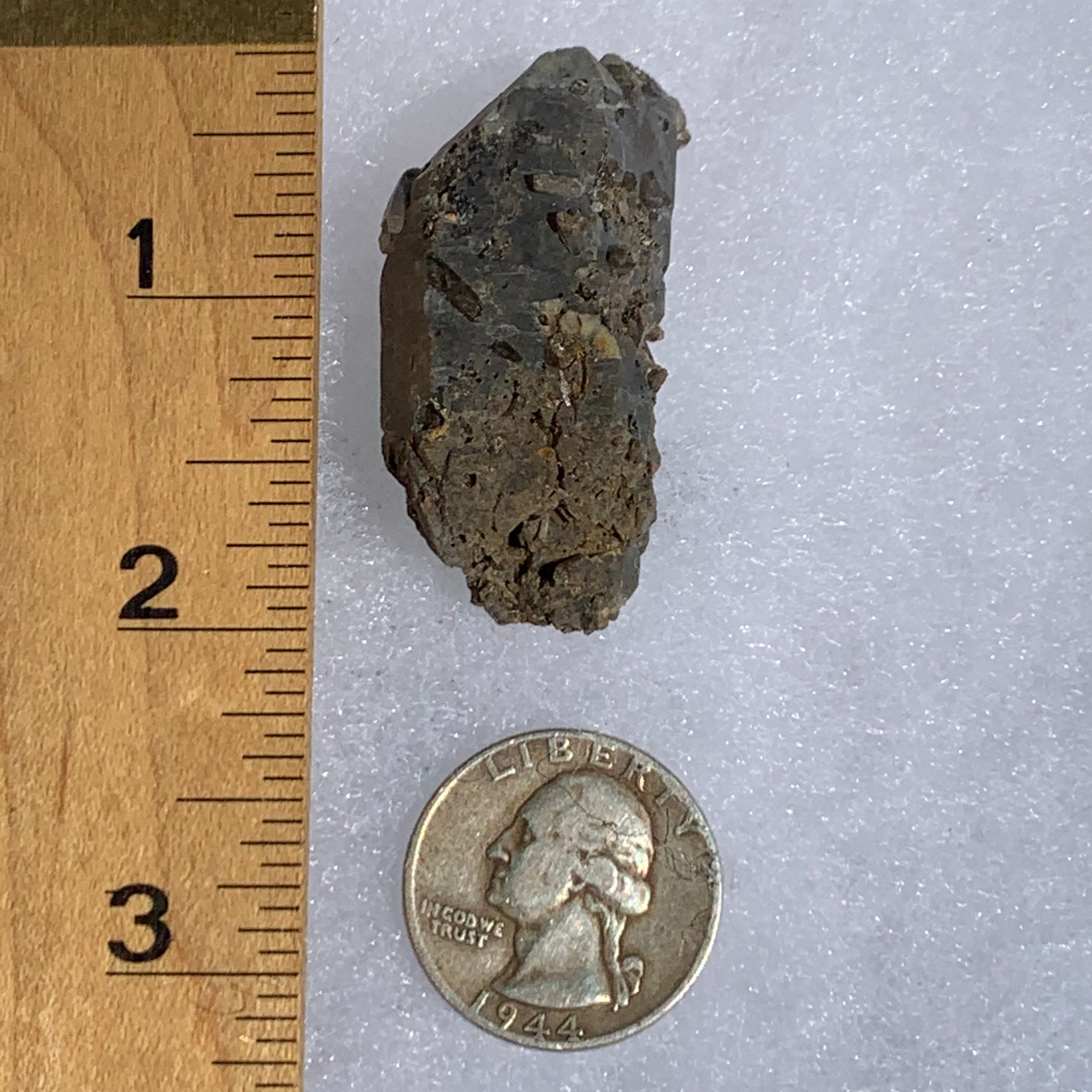 tiny brookite crystals on a smokey quartz cluster next to a ruler and a quarter for scale