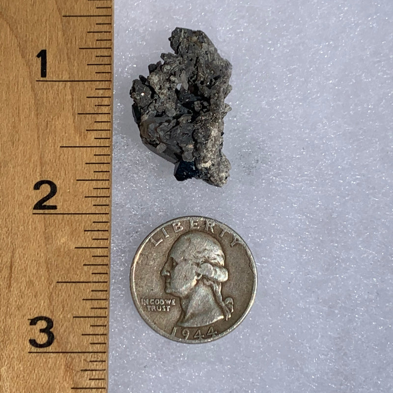 medium and tiny brookite crystals on a smokey quartz cluster next to a ruler and a quarter for scale