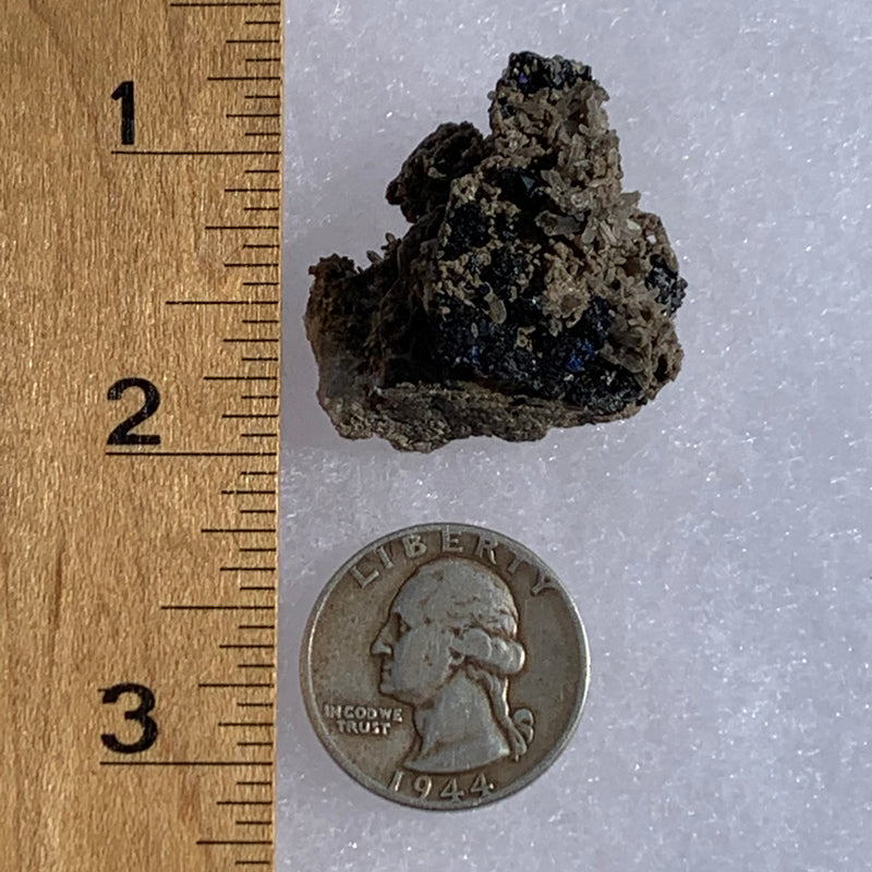large and small brookite crystals on a smokey quartz cluster next to a ruler and a quarter for scale