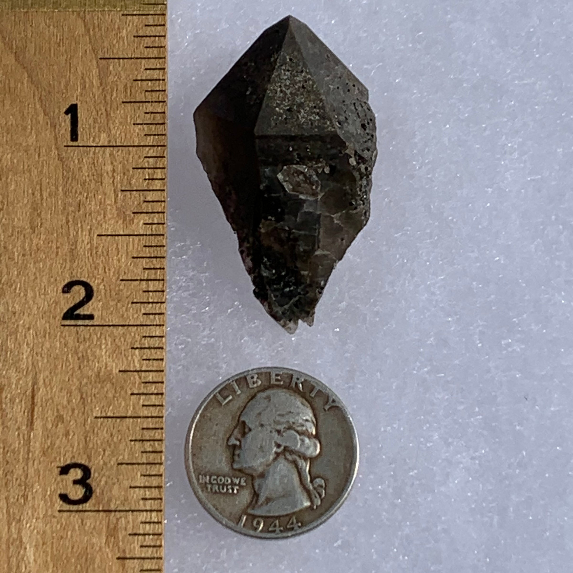 medium and tiny brookite crystals on a smokey quartz point next to a ruler and a quarter for scale