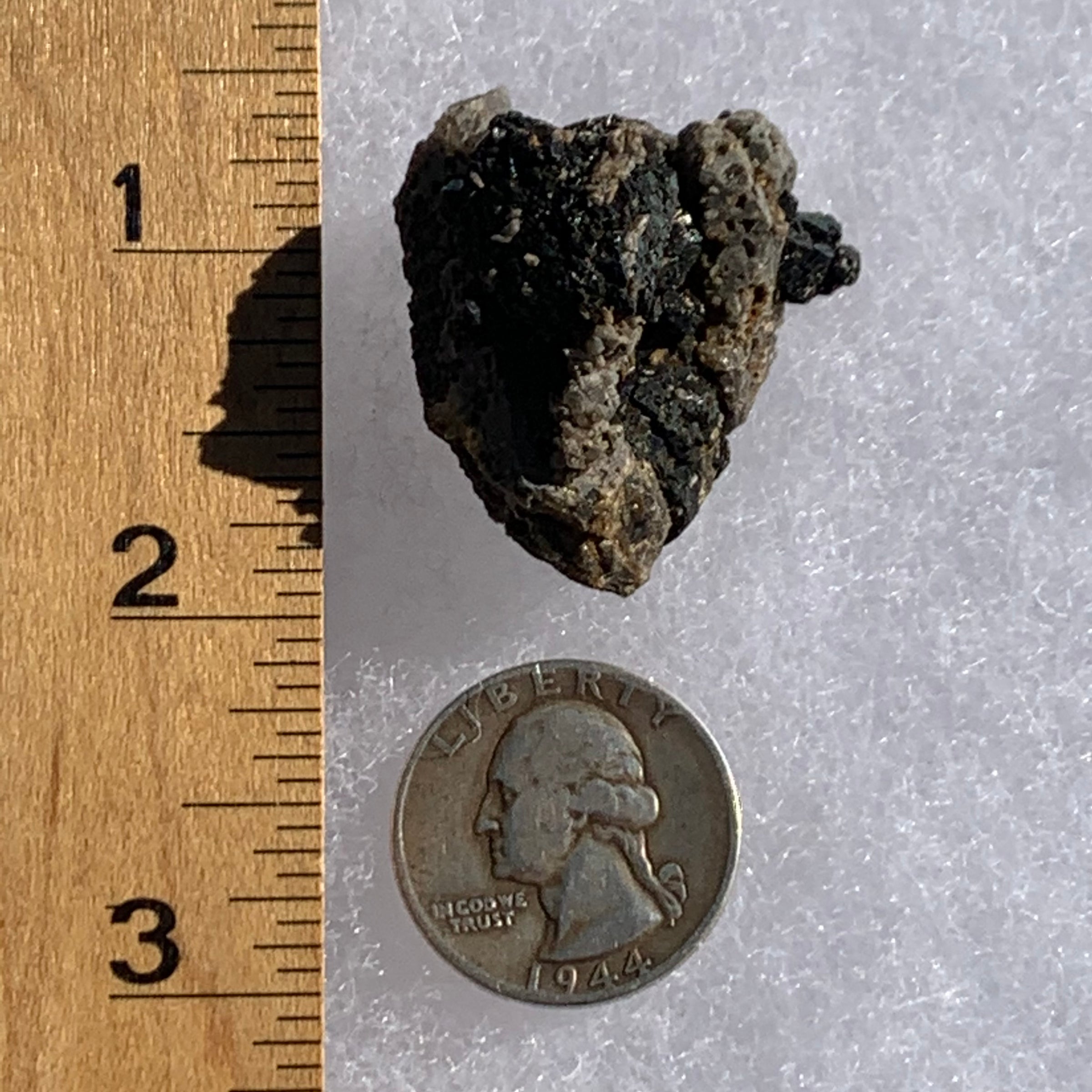 large brookite crystals on a smokey quartz cluster next to a ruler and a quarter for scale