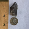 tiny brookite crystals on a smokey quartz point next to a ruler and a quarter for scale