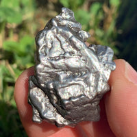 silver campo del cielo meteorite held in hand to show details