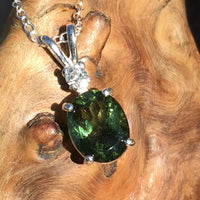 Moldavite and Brazilian phenacite pendant necklace displayed on driftwood