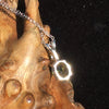the back of the Moldavite and Brazilian phenacite pendant necklace displayed on driftwood