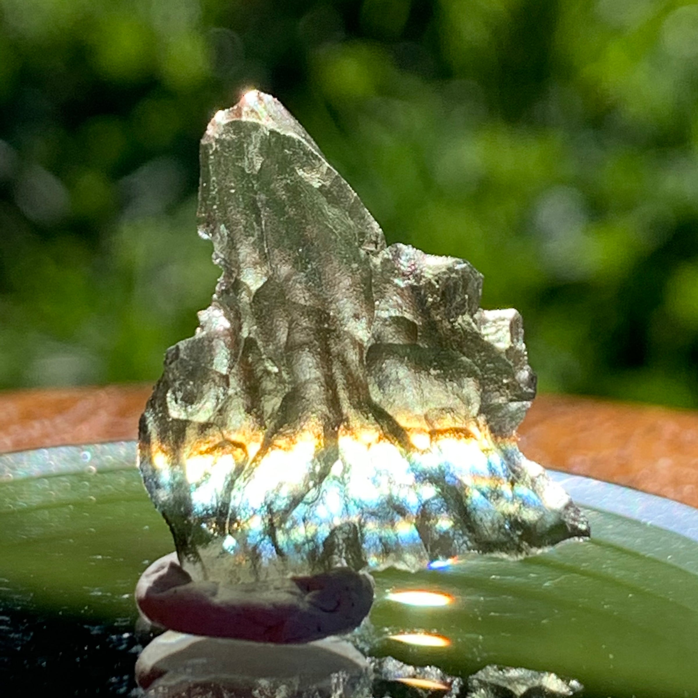 light reflects a rainbow through the thin green besednice moldavite tektite on display