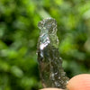 thin green besednice moldavite tektite held up on display to show details