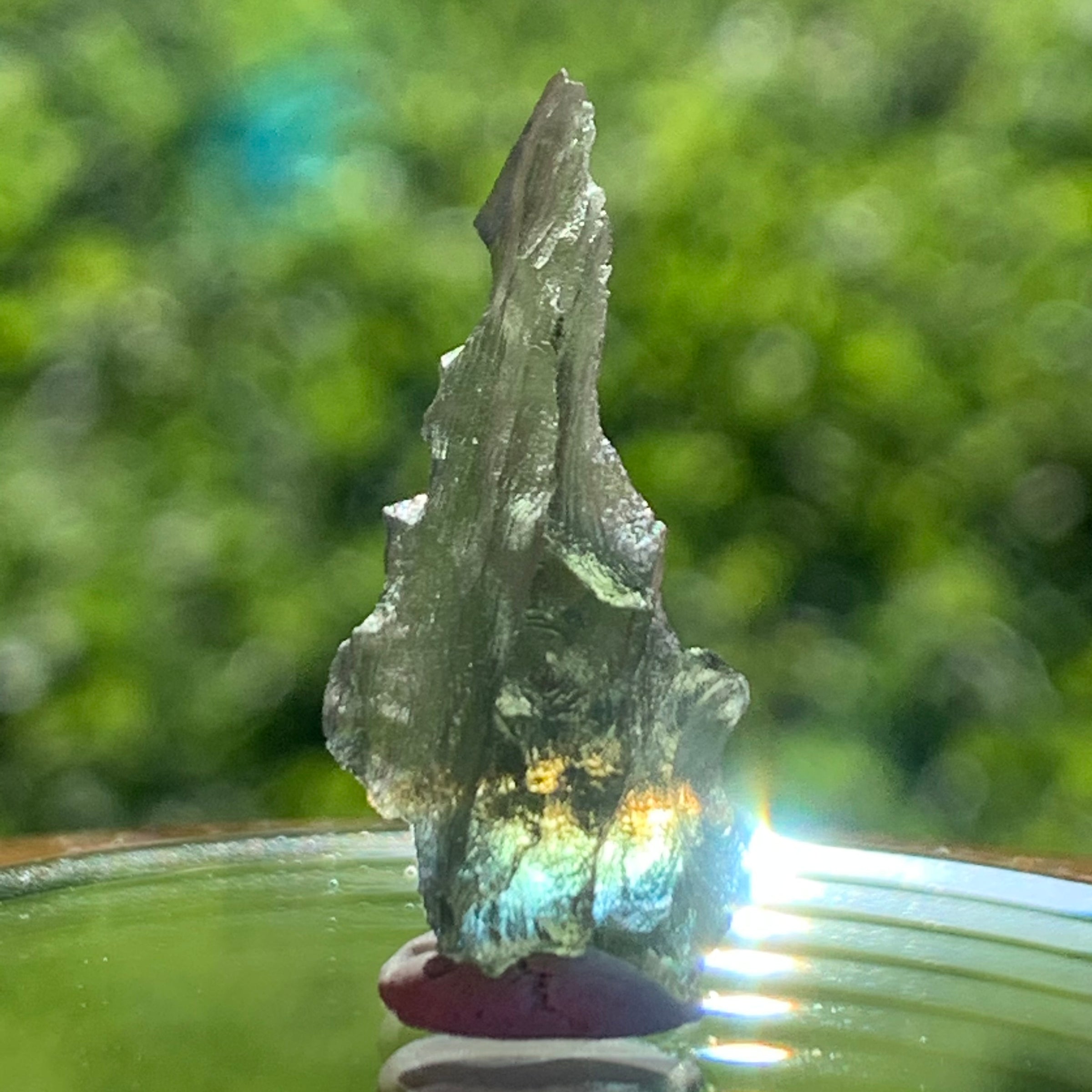 light reflects a rainbow through the thin green besednice moldavite tektite on display