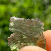 thin green besednice moldavite tektite held up on display to show details