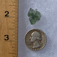 thin green besednice moldavite tektite next to a ruler and US quarter for scale