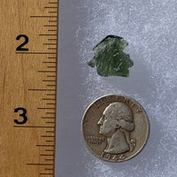 thin green besednice moldavite tektite next to a ruler and US quarter for scale