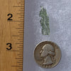 thin green besednice moldavite tektite next to a ruler and US quarter for scale