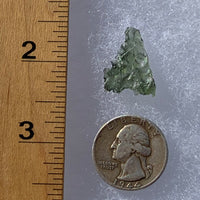 thin green besednice moldavite tektite next to a ruler and US quarter for scale