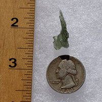 thin green besednice moldavite tektite next to a ruler and US quarter for scale