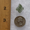 thin green besednice moldavite tektite next to a ruler and US quarter for scale