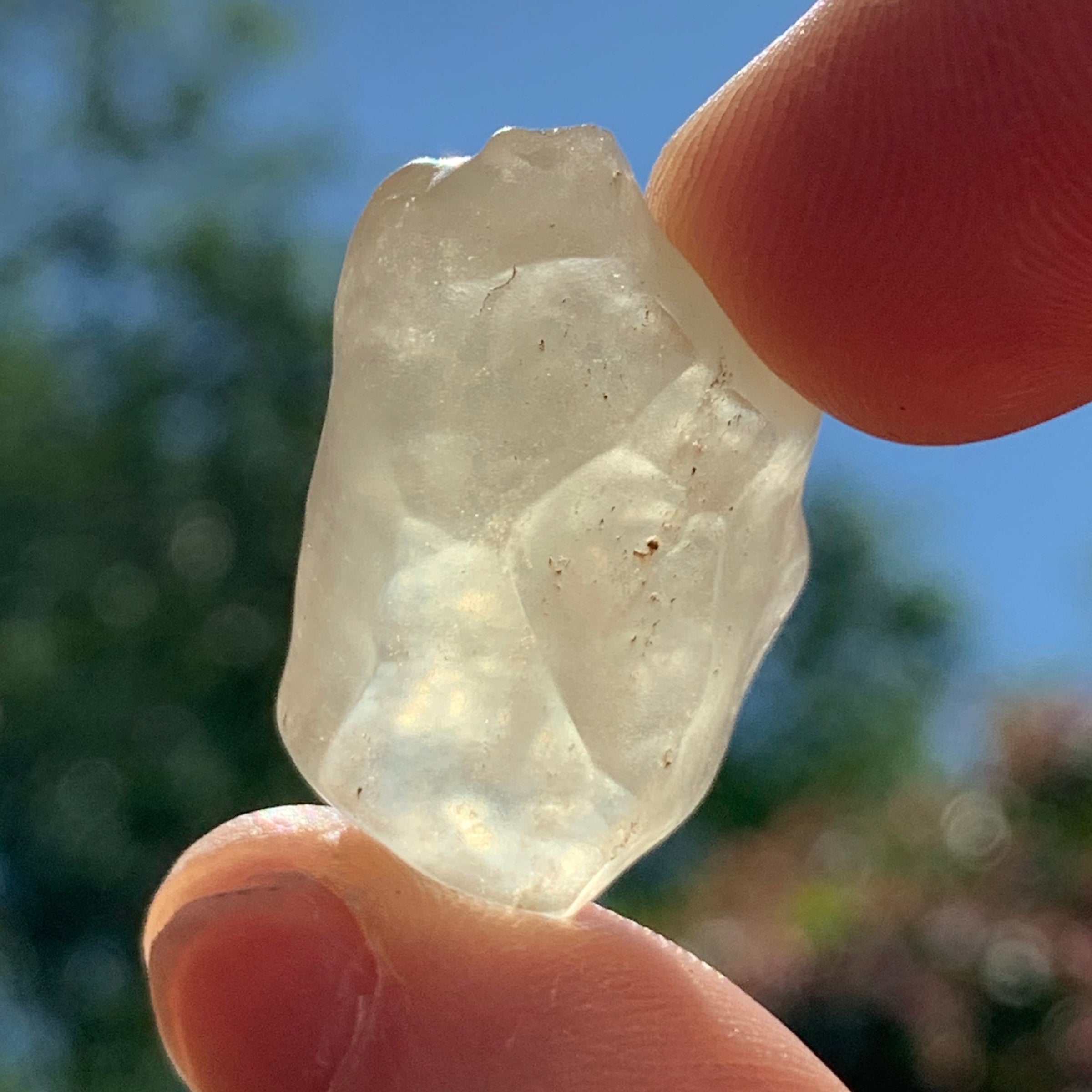 libyan desert glass is held up with sunlight shining through it