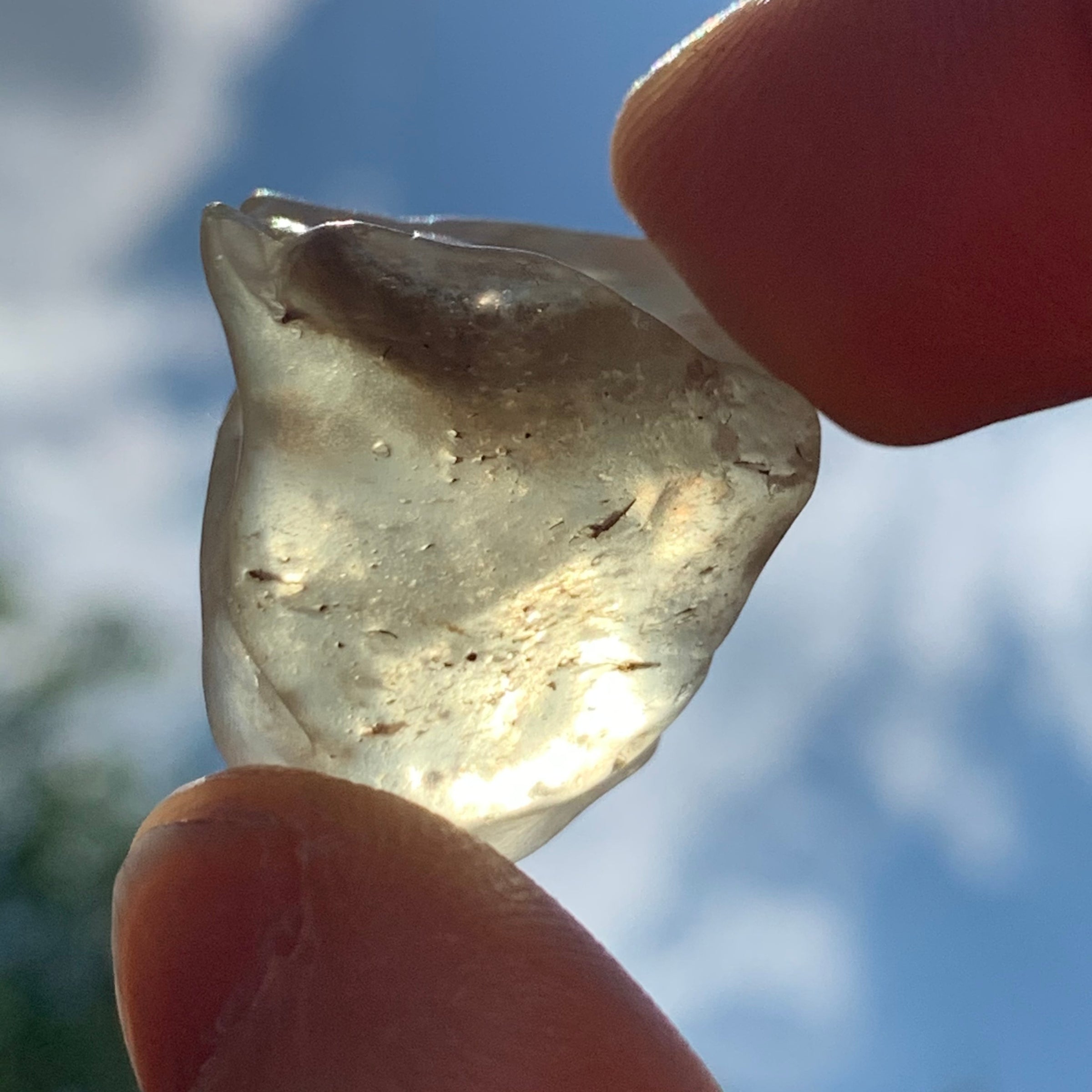 libyan desert glass is held up with sunlight shining through it